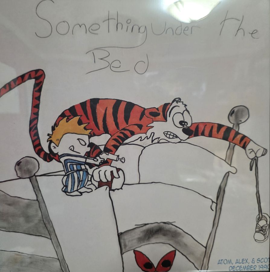 Hand-drawn mural of a boy and his tiger peering nervously over the edge of a bed at red eyes below, titled Something Under the Bed and signed Atom, Alex, & Scott, December 1990