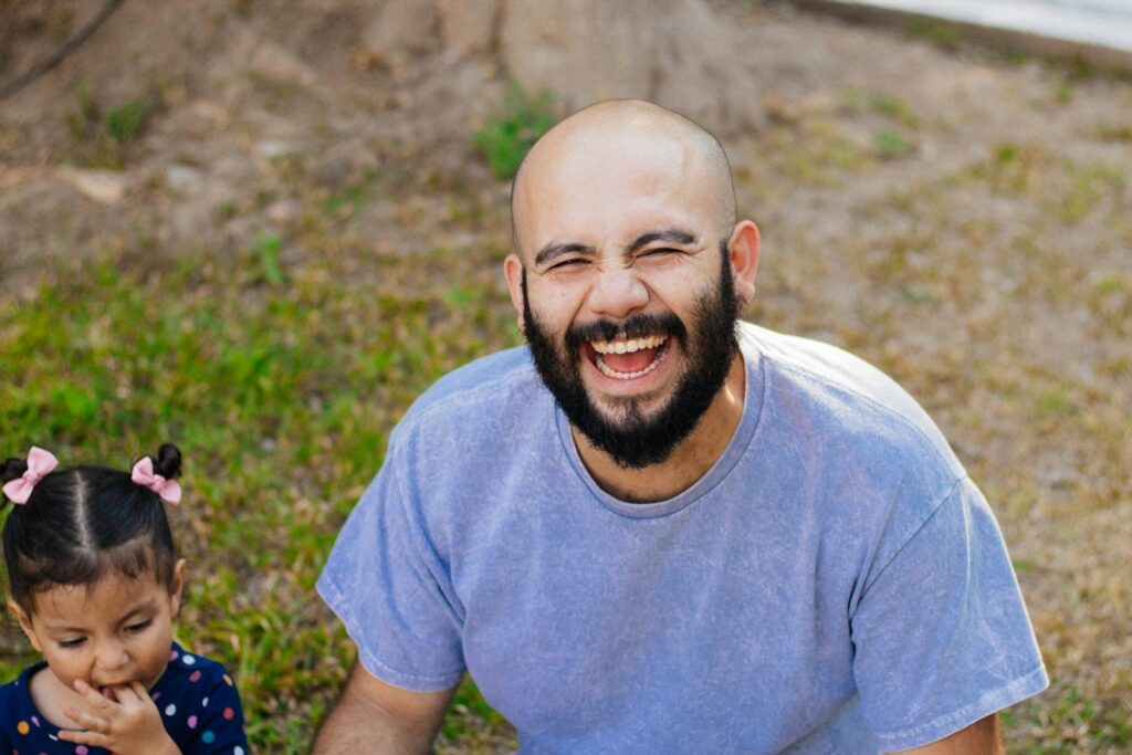 A father laughing with his little girl in the backyard