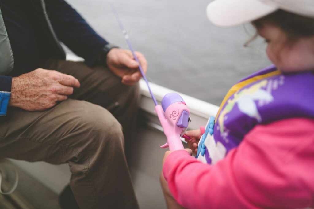 A grandfather helping a child with a fishing rod